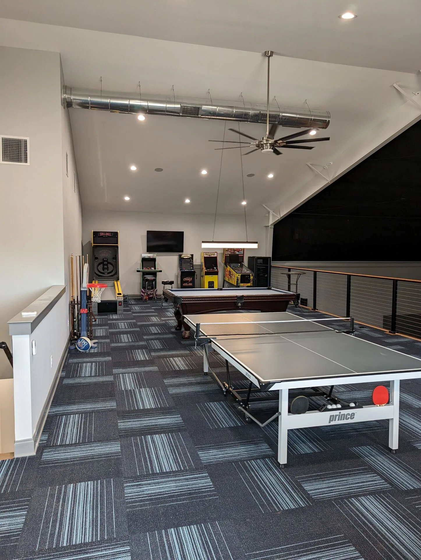 Game room with pool table, ping-pong, arcade cabinets, and high vaulted ceiling
